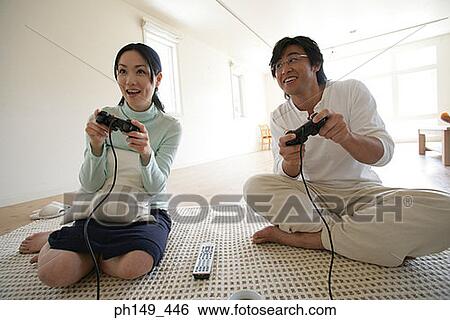 Young couple sitting on a mat and playing video games View Large Photo Image Stock Photograph - Young couple sitting on a mat and playing video games. Fotosearch