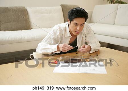 Young man assembling a model of an airship View Large Photo Image Stock Photo - Young man assembling a model of an airship. Fotosearch