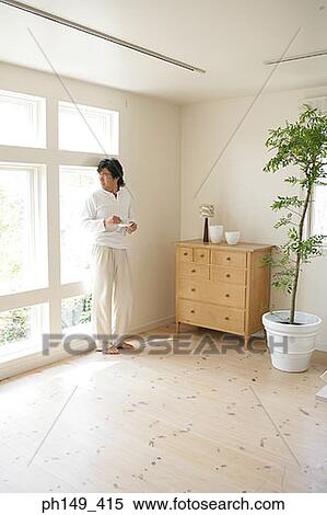 Young man holding a cup of tea and looking out of a window View Large Photo Image Stock Photography - Young man holding a cup of tea and looking out of a window. Fotosearch