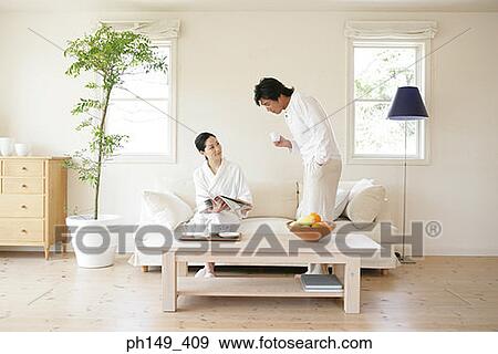Young man standing beside a young woman and reading a magazine View Large Photo Image Stock Photo - Young man standing beside a young woman and reading a magazine. Fotosearch