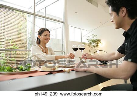 Young woman and a young man toasting with red wine at the dining table View Large Photo Image Stock Photo - Young woman and a young man toasting with red wine at the dining table. Fotosearch