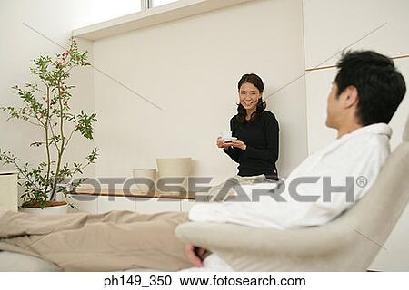 Young woman holding a cup and looking at a young man View Large Photo Image Stock Image - Young woman holding a cup and looking at a young man. Fotosearch