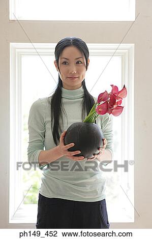 Young woman holding flowers in a vase View Large Photo Image Stock Image - Young woman holding flowers in a vase. Fotosearch