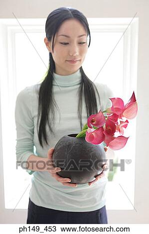 Young woman holding flowers in a vase View Large Photo Image Stock Image - Young woman holding flowers in a vase. Fotosearch