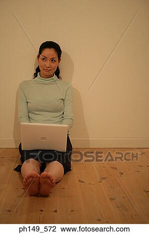 Young woman leaning against a wall with a laptop on her lap View Large Photo Image Stock Image - Young woman leaning against a wall with a laptop on her lap. Fotosearch