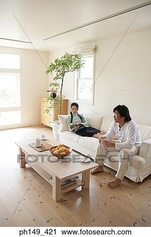 Young woman reading a magazine with a young man holding a cup of tea View Large Photo Image Stock Image - Young woman reading a magazine with a young man holding a cup of tea. Fotosearch