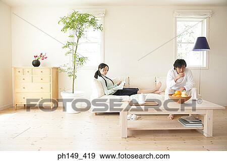 Young woman reading a magazine with a young man drinking a cup of tea View Large Photo Image Stock Photo - Young woman reading a magazine with a young man drinking a cup of tea. Fotosearch