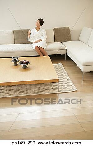 Young woman sitting on a couch View Large Photo Image Stock Photo - Young woman sitting on a couch. Fotosearch