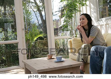 Young woman sitting on a couch View Large Photo Image Stock Photo - Young woman sitting on a couch. Fotosearch