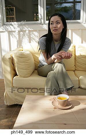 Young woman sitting on a couch View Large Photo Image Stock Photo - Young woman sitting on a couch. Fotosearch