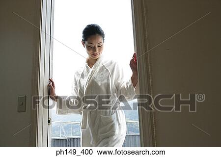 Stock Image - Young woman standing at the doorway. Fotosearch