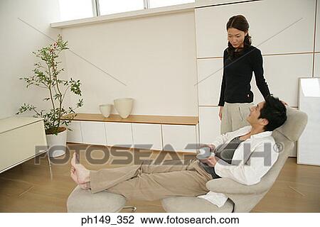 Young woman standing near a young man sitting in an armchair View Large Photo Image Stock Image - Young woman standing near a young man sitting in an armchair. Fotosearch