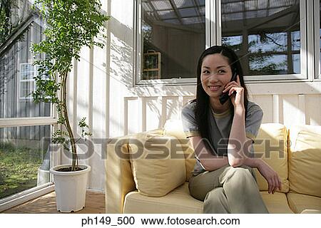 Young woman talking on a mobile phone and smiling View Large Photo Image Stock Image - Young woman talking on a mobile phone and smiling. Fotosearch