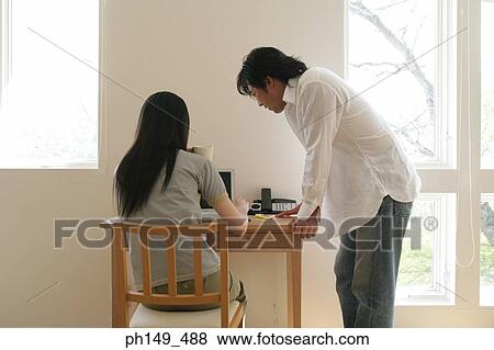 Young woman using a laptop with a young man standing beside her View Large Photo Image Stock Photo - Young woman using a laptop with a young man standing beside her. Fotosearch