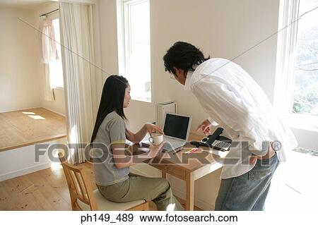 Young woman using a laptop with a young man pointing at the screen beside her View Large Photo Image Stock Photo - Young woman using a laptop with a young man pointing at the screen beside her. Fotosearch