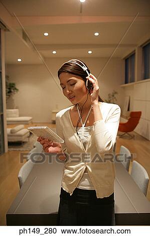 Young woman wearing headphones and holding a CD case View Large Photo Image Stock Image - Young woman wearing headphones and holding a CD case. Fotosearch