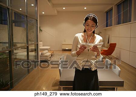 Stock Photo - Young woman wearing headphones and holding a CD case. Fotosearch
