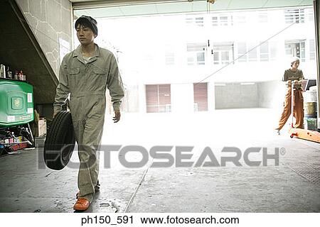 Auto mechanic holding a flat tire View Large Photo Image Stock Image - Auto mechanic holding a flat tire. Fotosearch