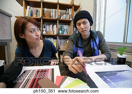 Stock Image - Businessman and a businesswoman sitting in an office. Fotosearch