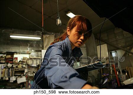 Close-up of a female auto mechanic examining an engine View Large Photo Image Stock Photo - Close-up of a female auto mechanic examining an engine. Fotosearch