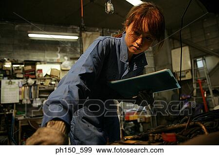 Close-up of a female auto mechanic examining an engine View Large Photo Image Stock Photo - Close-up of a female auto mechanic examining an engine. Fotosearch
