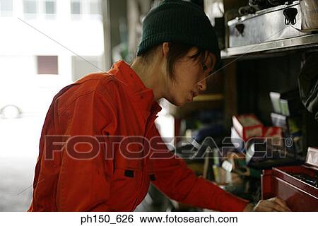 Close-up of a female auto mechanic standing in an auto repair shop View Large Photo Image Stock Photograph - Close-up of a female auto mechanic standing in an auto repair shop. Fotosearch