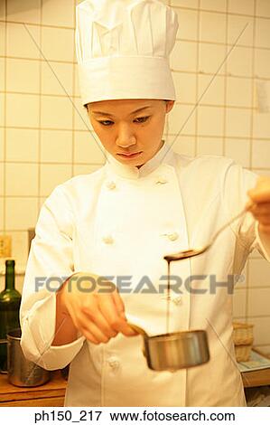Close-up of a female chef checking sauce in a pan with a spoon View Large Photo Image Stock Photo - Close-up of a female chef checking sauce in a pan with a spoon. Fotosearch