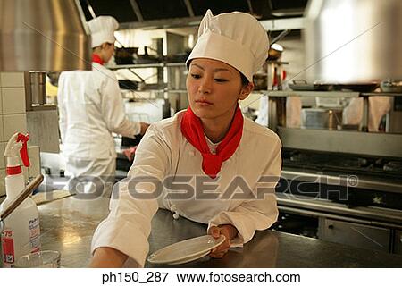 Close-up of a female chef cleaning a plate in the kitchen View Large Photo Image Stock Photo - Close-up of a female chef cleaning a plate in the kitchen. Fotosearch