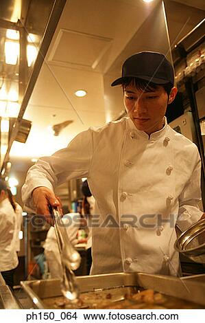 Close-up of a male chef preparing food with his colleagues View Large Photo Image Picture - Close-up of a male chef preparing food with his colleagues. Fotosearch