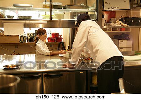 Stock Photograph - Close-up of a waiter and a waitress standing in the kitchen. Fotosearch
