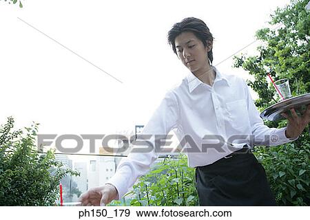 Close-up of a waiter holding a serving tray and picking up a glass View Large Photo Image Stock Photo - Close-up of a waiter holding a serving tray and picking up a glass. Fotosearch