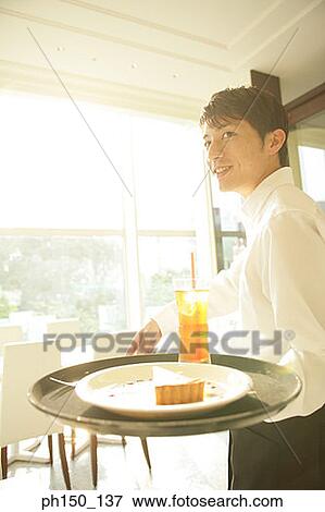 Close-up of a waiter standing and holding a tray View Large Photo Image Stock Photo - Close-up of a waiter standing and holding a tray. Fotosearch