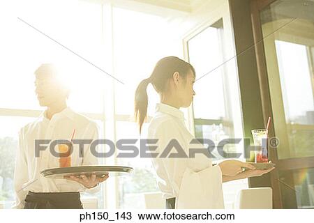 Close-up of a waiter standing with a waitress and holding trays View Large Photo Image Stock Image - Close-up of a waiter standing with a waitress and holding trays. Fotosearch