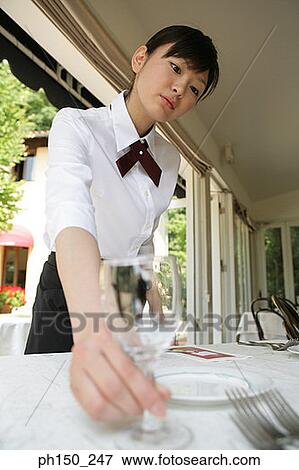Close-up of a waitress arranging place settings on the table View Large Photo Image Stock Photo - Close-up of a waitress arranging place settings on the table. Fotosearch