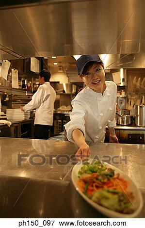 Stock Photo - Close-up of a waitress holding a plate of food. Fotosearch