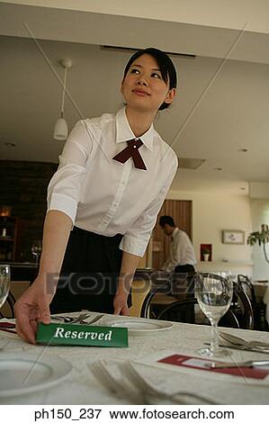 Stock Photo - Close-up of a waitress putting a reserved sign on the table. Fotosearch