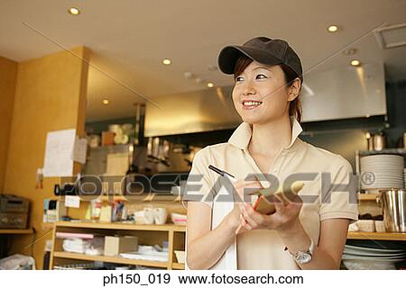 Close-up of a waitress writing on a notepad and smiling View Large Photo Image Stock Photo - Close-up of a waitress writing on a notepad and smiling. Fotosearch