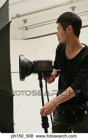 Close-up of a young man adjusting lighting equipment in a film studio View Large Photo Image Stock Photo - Close-up of a young man adjusting lighting equipment in a film studio. Fotosearch