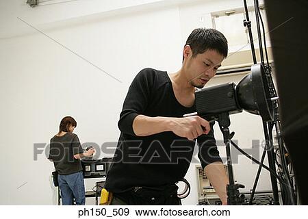 Close-up of a young man adjusting lighting equipment in a film studio View Large Photo Image Stock Photo - Close-up of a young man adjusting lighting equipment in a film studio. Fotosearch