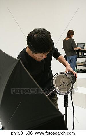 Stock Photograph - Close-up of a young man adjusting lighting equipment in a film studio. Fotosearch