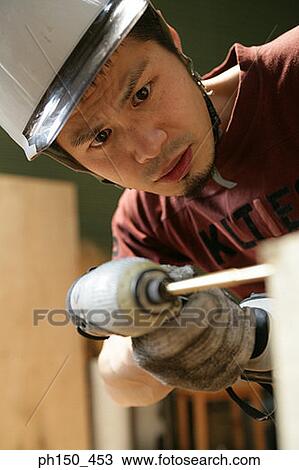 Close-up of a young man drilling a hole in wood View Large Photo Image Stock Image - Close-up of a young man drilling a hole in wood. Fotosearch