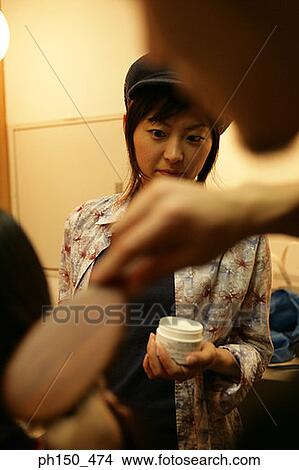 Picture - Close-up of a young woman holding a jar of moisturizer. Fotosearch