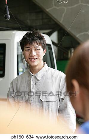 Close-up of an auto mechanic standing in an auto repair shop and smiling View Large Photo Image Picture - Close-up of an auto mechanic standing in an auto repair shop and smiling. Fotosearch