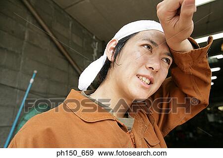 Close-up of an auto mechanic wiping his forehead View Large Photo Image Stock Photo - Close-up of an auto mechanic wiping his forehead. Fotosearch