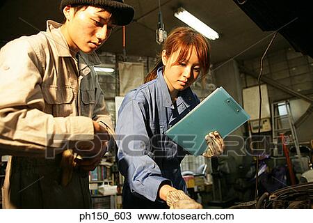 Close-up of two auto mechanics examining an engine of a car View Large Photo Image Stock Image - Close-up of two auto mechanics examining an engine of a car. Fotosearch