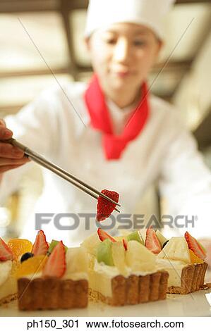 Female chef decorating a tart with a slice of strawberry View Large Photo Image Stock Image - Female chef decorating a tart with a slice of strawberry. Fotosearch