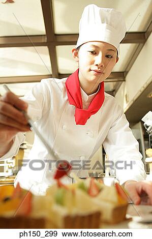 Female chef decorating a tart with a slice of strawberry View Large Photo Image Stock Photo - Female chef decorating a tart with a slice of strawberry. Fotosearch