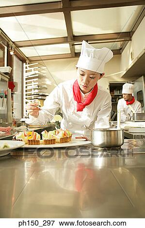 Female chef preparing a strawberry tart in a restaurant with a chef standing in the background View Large Photo Image Stock Photo - Female chef preparing a strawberry tart in a restaurant with a chef standing in the background. Fotosearch