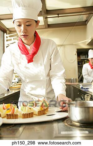 Female chef preparing a strawberry tart in a restaurant with a chef standing in the background View Large Photo Image Stock Photo - Female chef preparing a strawberry tart in a restaurant with a chef standing in the background. Fotosearch