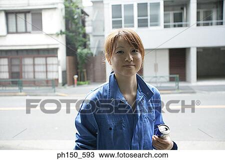 Stock Image - Portrait of a female auto mechanic holding a beer can. Fotosearch